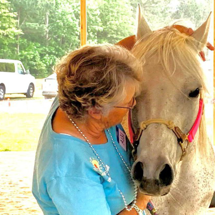 a woman is petting a white horse