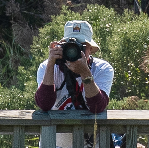 a man sitting on a bench taking a picture with his camera