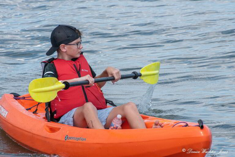 a man in an orange kayak paddles through the water