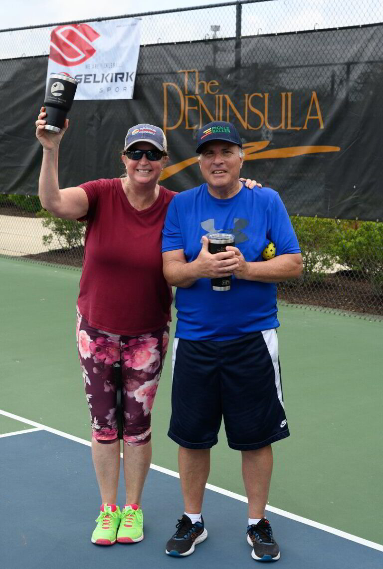 two people standing on a tennis court holding up a trophy
