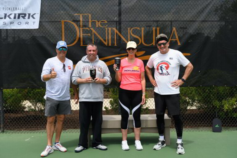 four people standing on a tennis court holding trophies