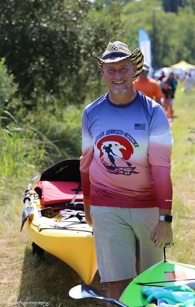 a man standing next to a kayak in the grass