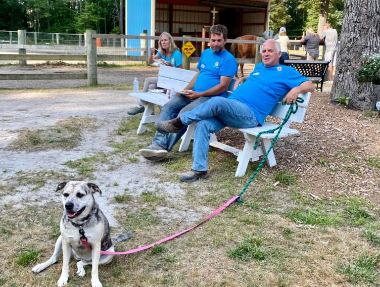 two men and a dog are sitting on benches