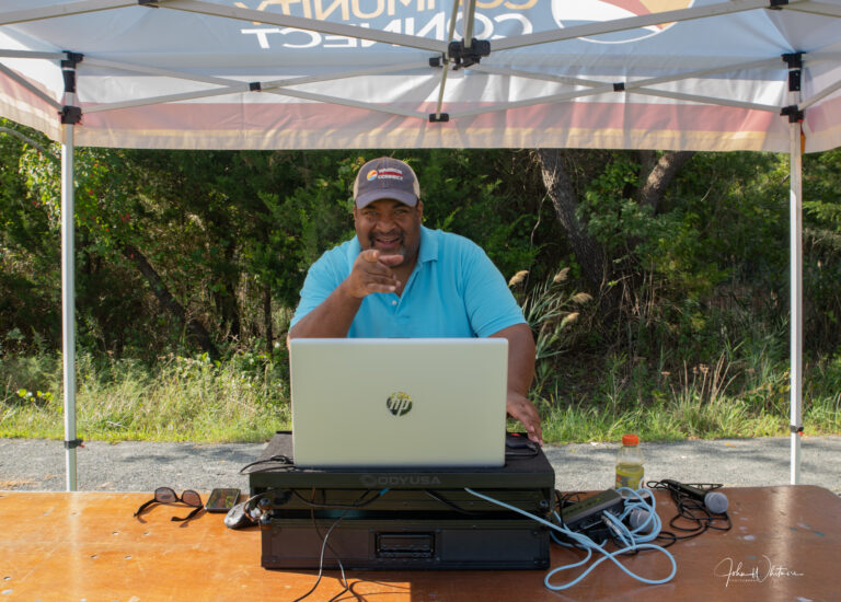 a man sitting in front of a laptop computer under a tent