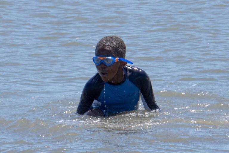 a young boy in a wet suit and goggles swimming