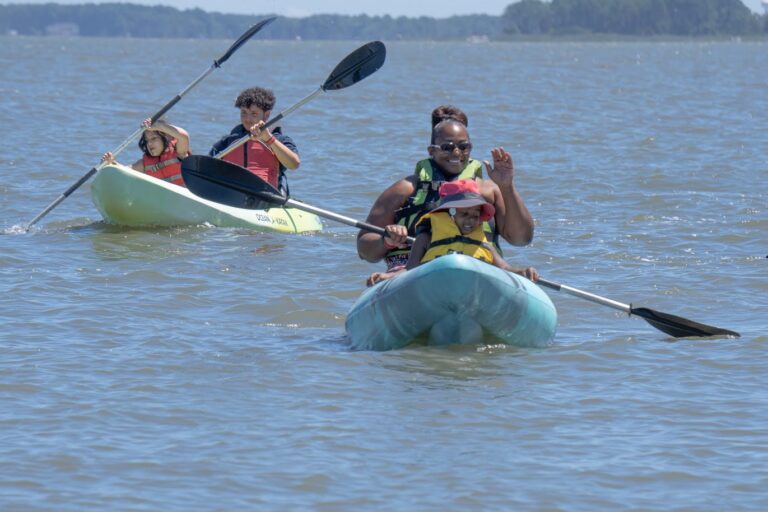 three people in kayaks paddling on the water