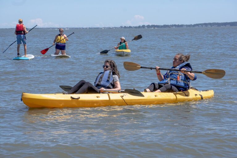 a group of people riding on top of kayaks in the water