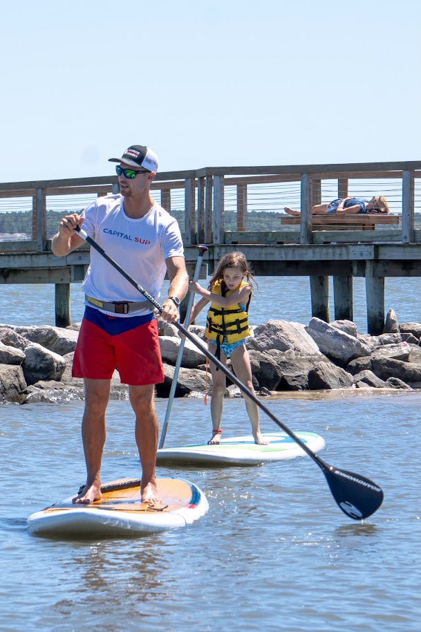 a man standing on a paddle board with a young girl