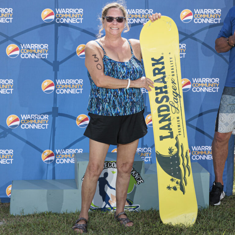 a woman holding a yellow snowboard in front of a wall