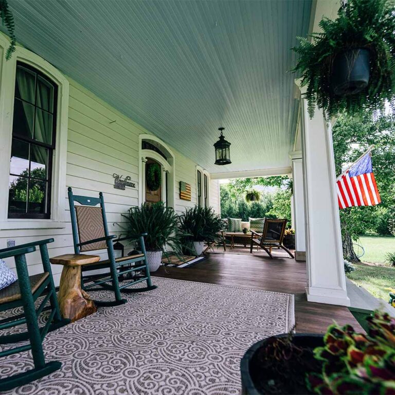 a porch with rocking chairs and an american flag