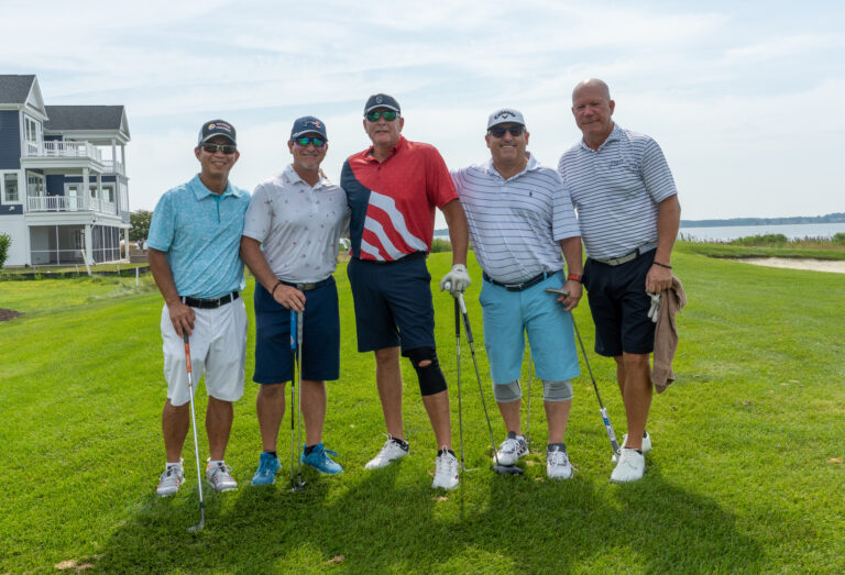 four men are posing for a picture on the golf course
