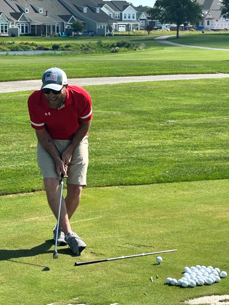 a man in red shirt and tan shorts playing golf