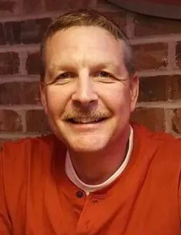 a man in an orange shirt is smiling
