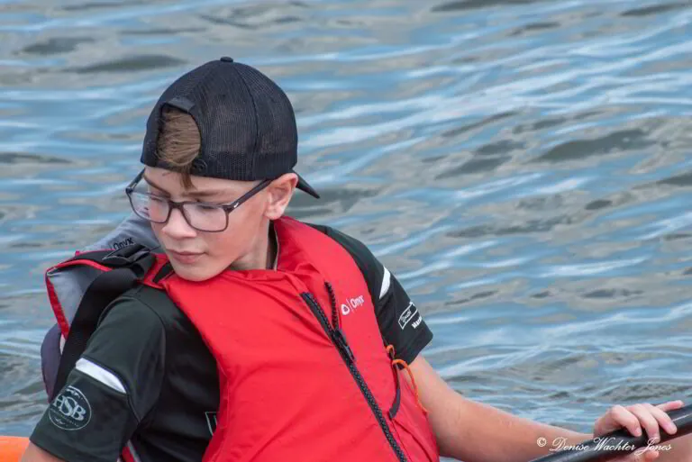 a boy in a life jacket paddling a boat