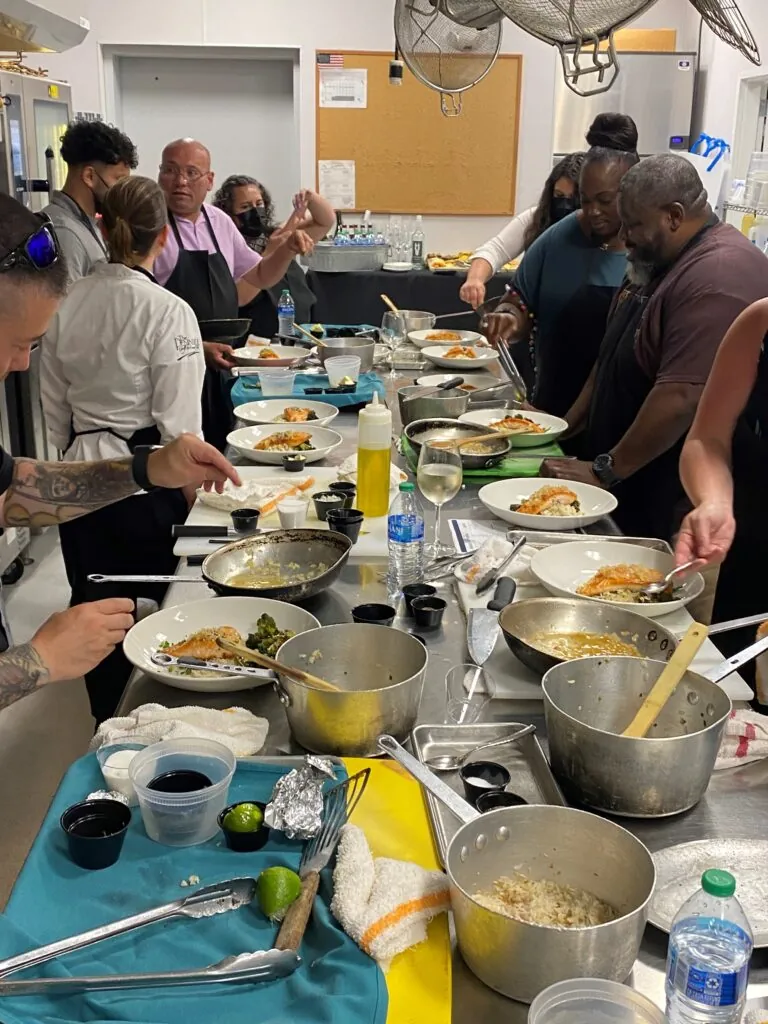 a group of people standing around a table filled with food